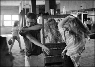 USA. New York City. 1959. Brooklyn Gang. Coney Island. Kathy fixing her hair in a cigarette machine mirror.